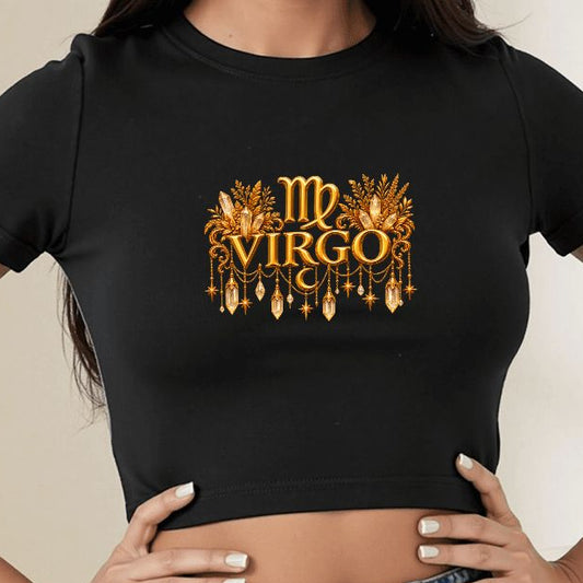 A woman wearing a fitted black crop top T-shirt with a gold chandelier and 'LEO' graphic on the chest, paired with a blue denim skirt in a brightly lit indoor room.