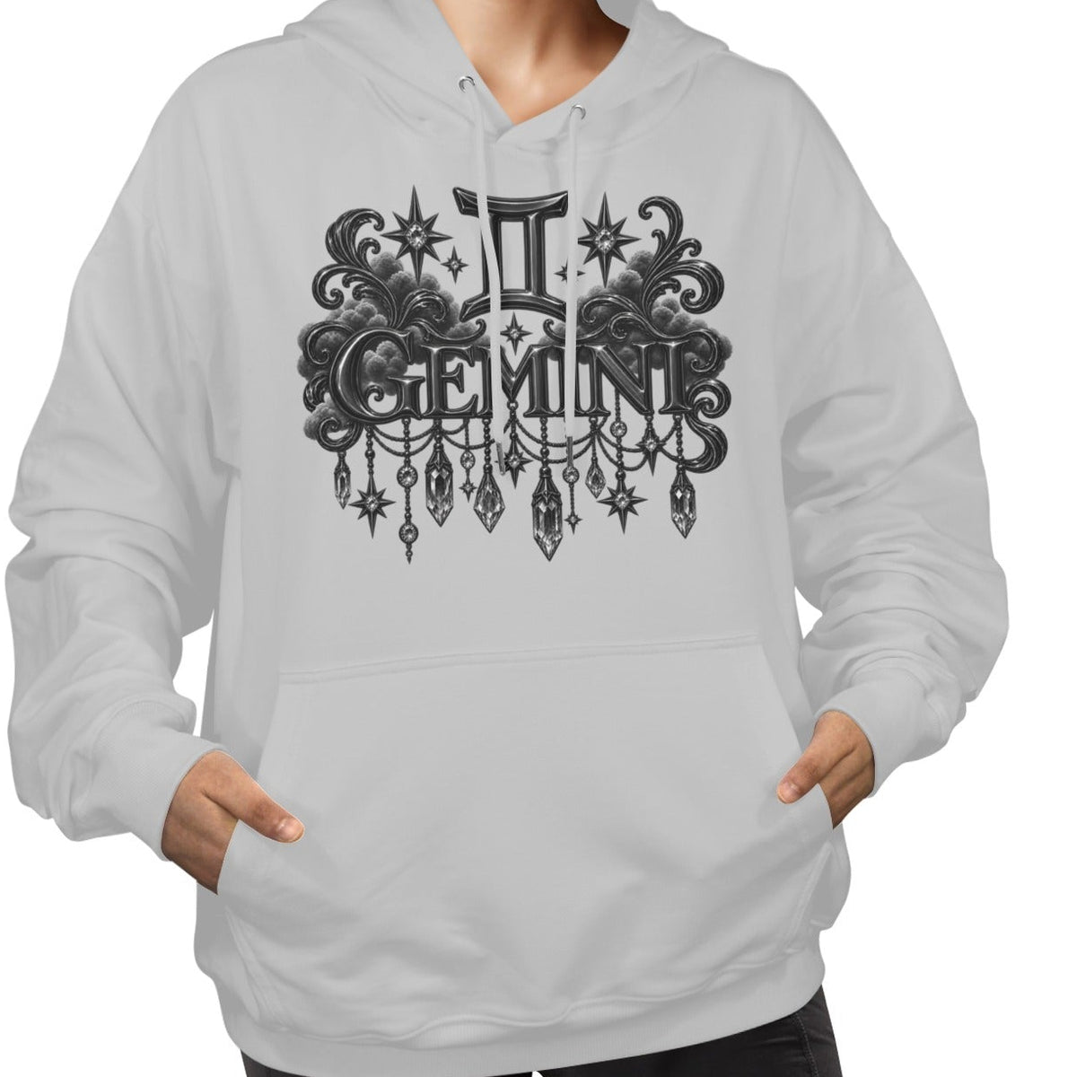 A woman wearing a light gray pullover hoodie with a black gothic-style Gemini zodiac graphic on the chest, paired with black pants, against a plain white background.