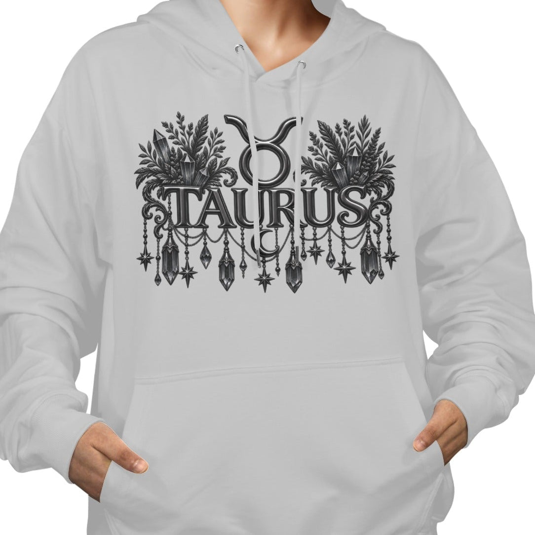 A woman wearing a light gray pullover hoodie with a black graphic print of the Taurus zodiac symbol and the word 'TAURUS' in an ornate font, shown against a plain white background.