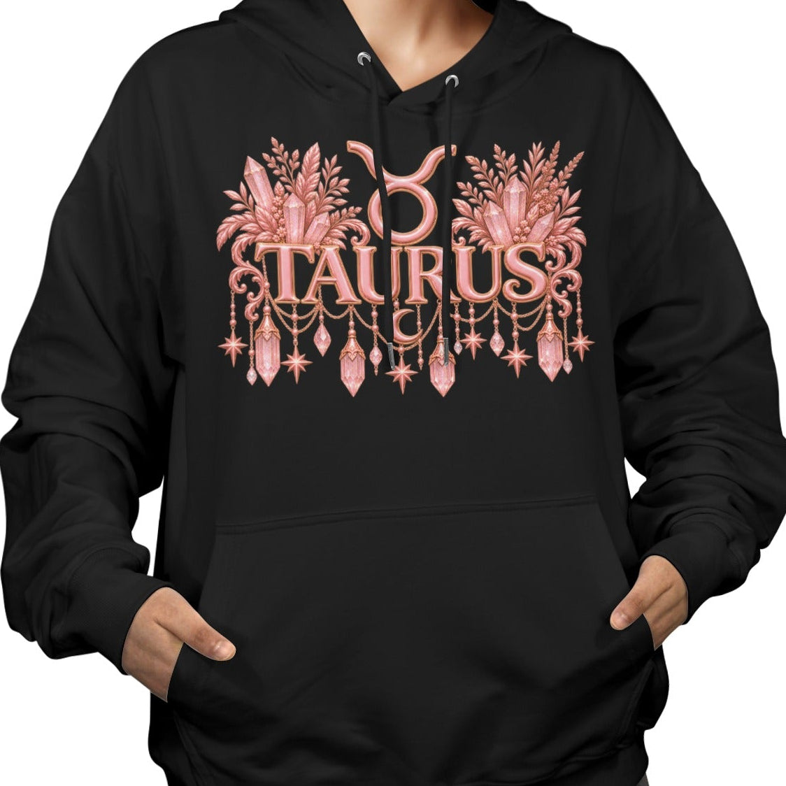 A woman wearing a black pullover hoodie with a pink and gold Taurus zodiac graphic on the chest, shown against a plain white background.