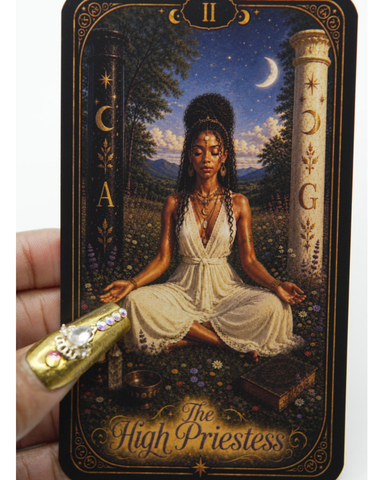 A hand holds a tarot card titled 'The High Priestess' against a plain white background. The card features an illustration of a woman in a white dress meditating under a crescent moon at night, with gold decorative borders and text.